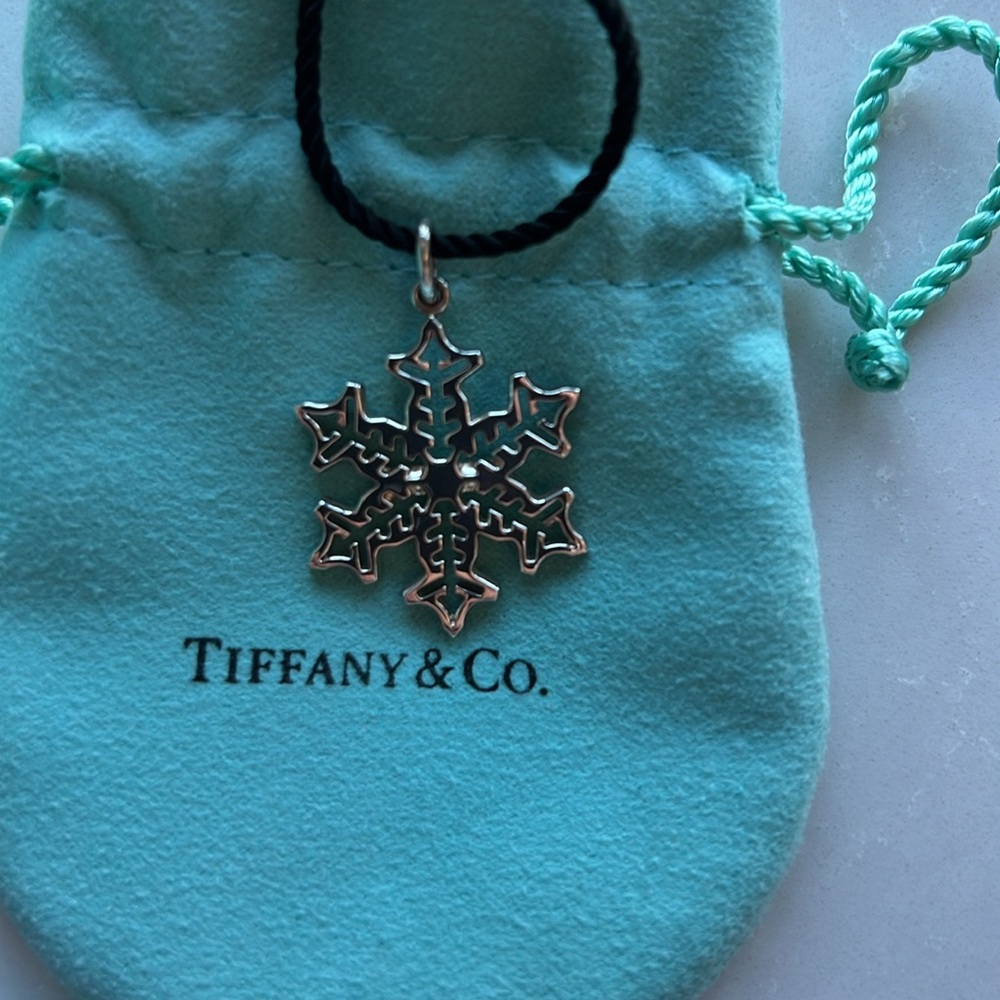 Tiffany & Co sterling silver snowflake on black cord.